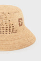 A close-up of a beige woven straw bucket hat, or bob en raphia, featuring a small brown embroidered number 5 on the side.