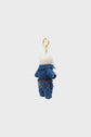 A small plush keychain charm peluche ourson featuring a blue denim outfit with white faux fur trim and a gold keyring attached at the top—an adorable accessoire mode inspired by Darel.