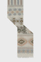 A cream-colored woven textile crafted from coton mélangé with geometric patterns in muted blue, peach, and olive green, featuring fringed edges and a diagonal fold displaying repeating diamond and floral motifs—an étole bohème accentuated by its motif ethnique charm.