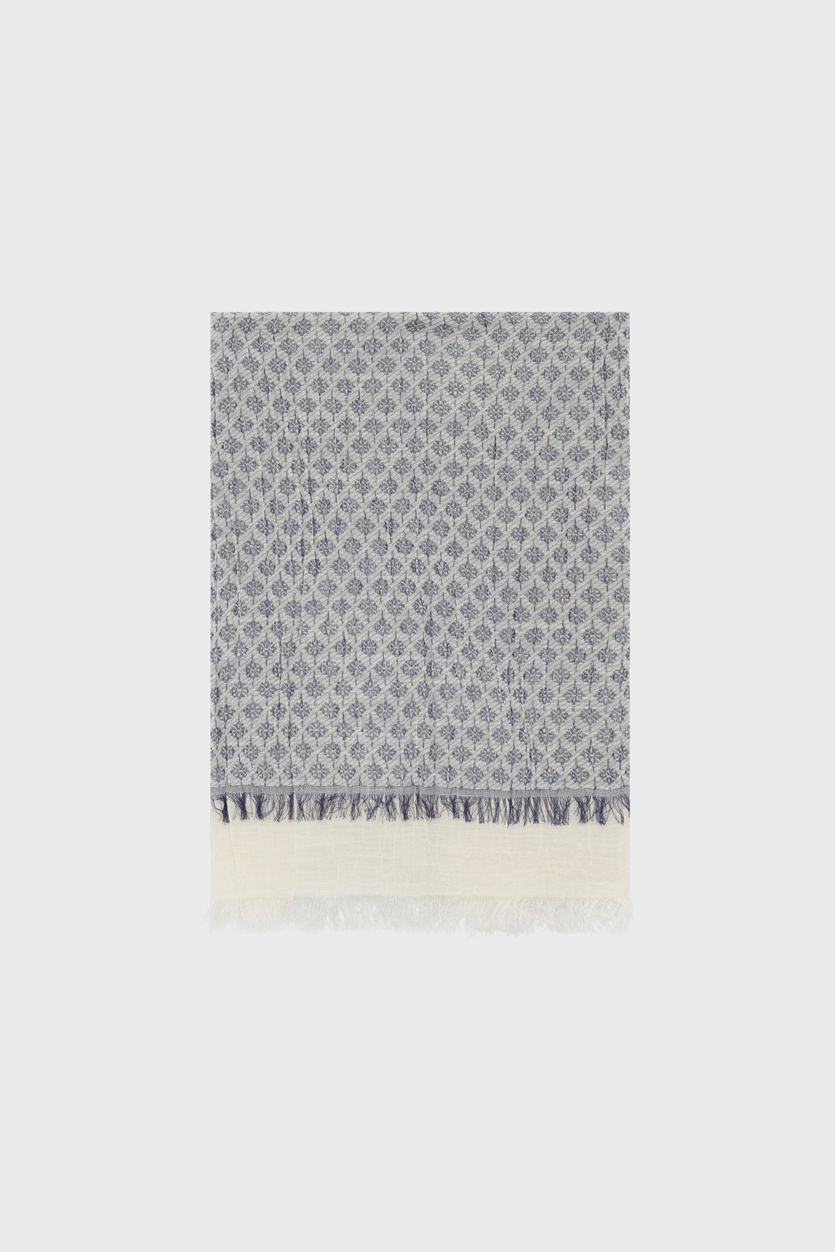 A folded rectangular foulard en coton with a blue and white geometric diamond motif bleu, featuring short fringe on one edge and a wide white border at the bottom. The textile exudes un style bohème and is displayed against a plain light background.