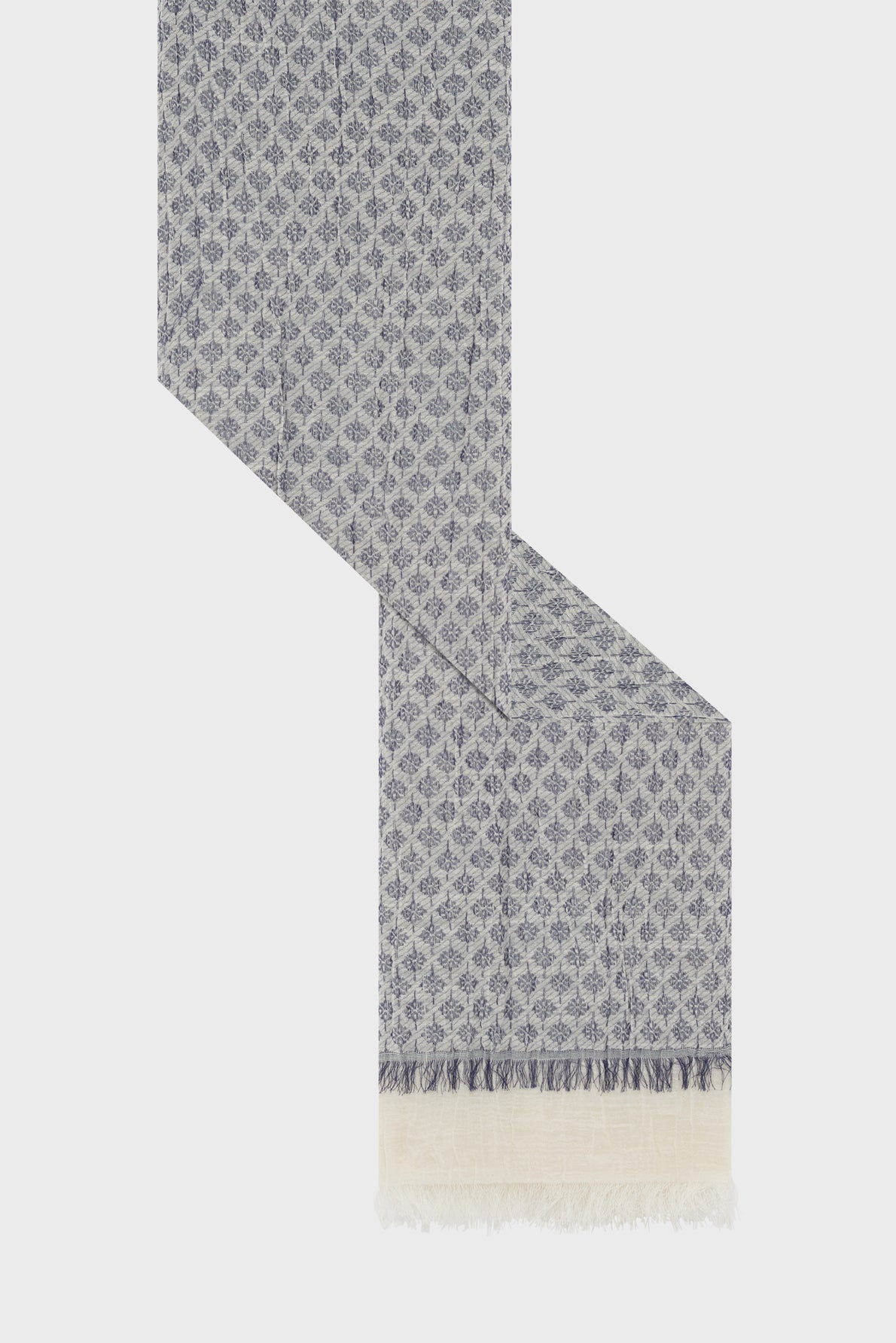 A long, woven foulard en coton with a blue and white geometric diamond motif bleu, ending in a cream fringe. The scarf is laid out against a plain white background in a zig-zag shape, adding a touch of style bohème to any outfit.