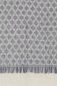A close-up of a woven fabric with a blue geometric pattern, or motif bleu, on a white background. The bottom edge of the foulard en coton is adorned with blue and white fringes, perfect for adding une touche de style bohème to your look.