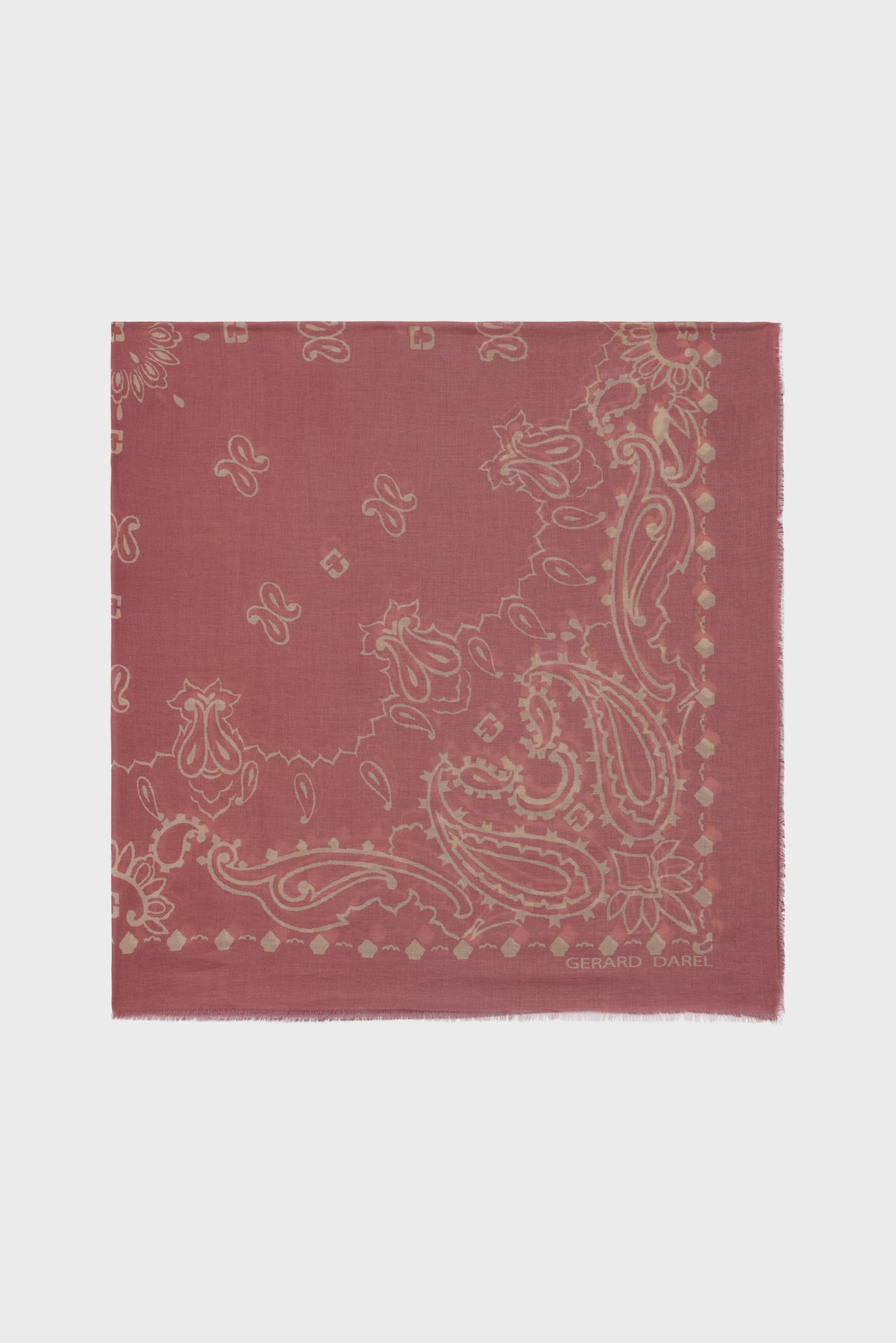 A square, dusty rose carré bandana crafted from soft coton, featuring a beige paisley and floral motif with subtle geometric accents. The text Gerard Darel is printed in the bottom right corner, and the edges are slightly frayed.