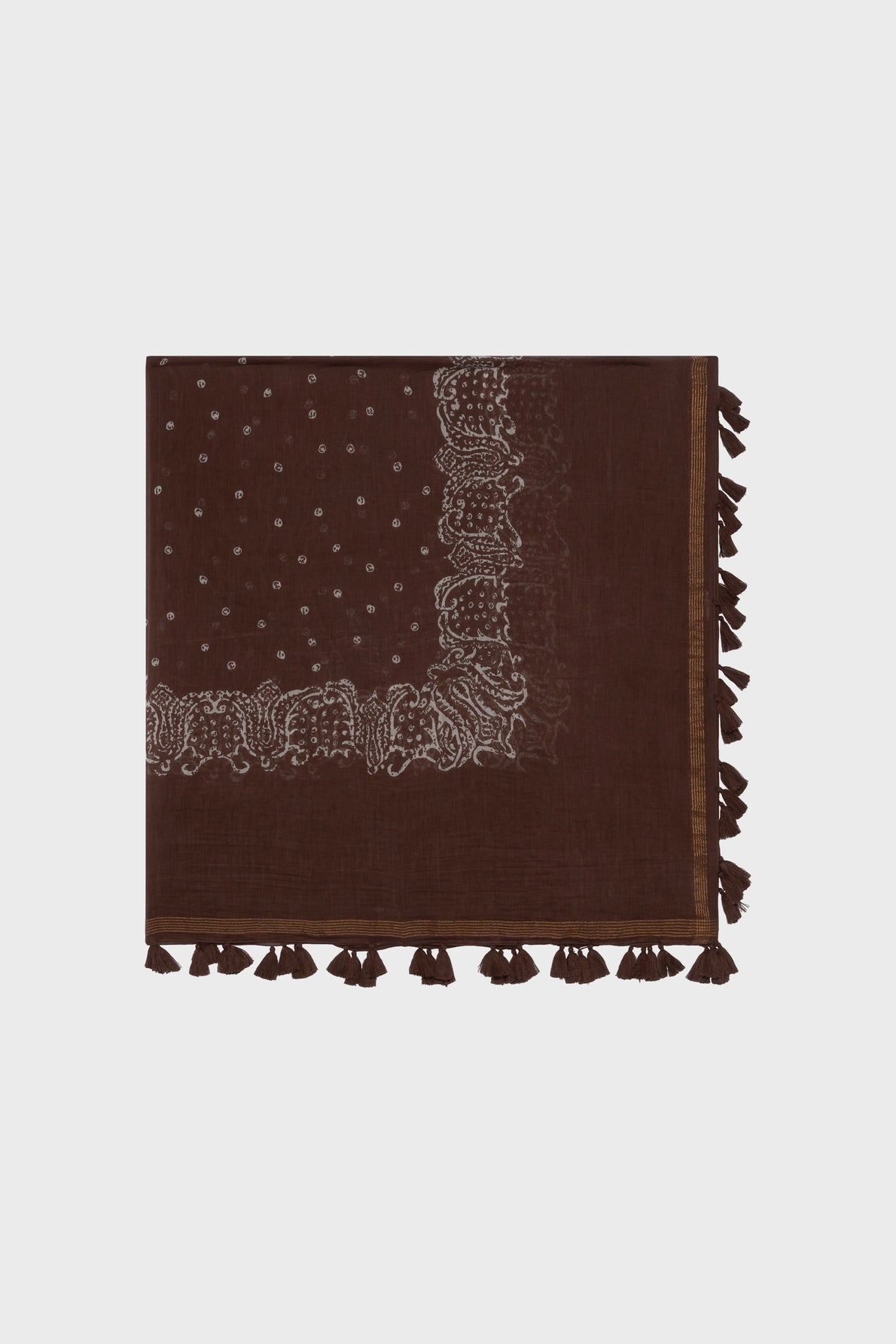 A folded brown carré coton soie scarf with white embroidered patterns along the edges and small white dots. The scarf features decorative tassels and motif ethnique accents, adding a unique touch along one side.