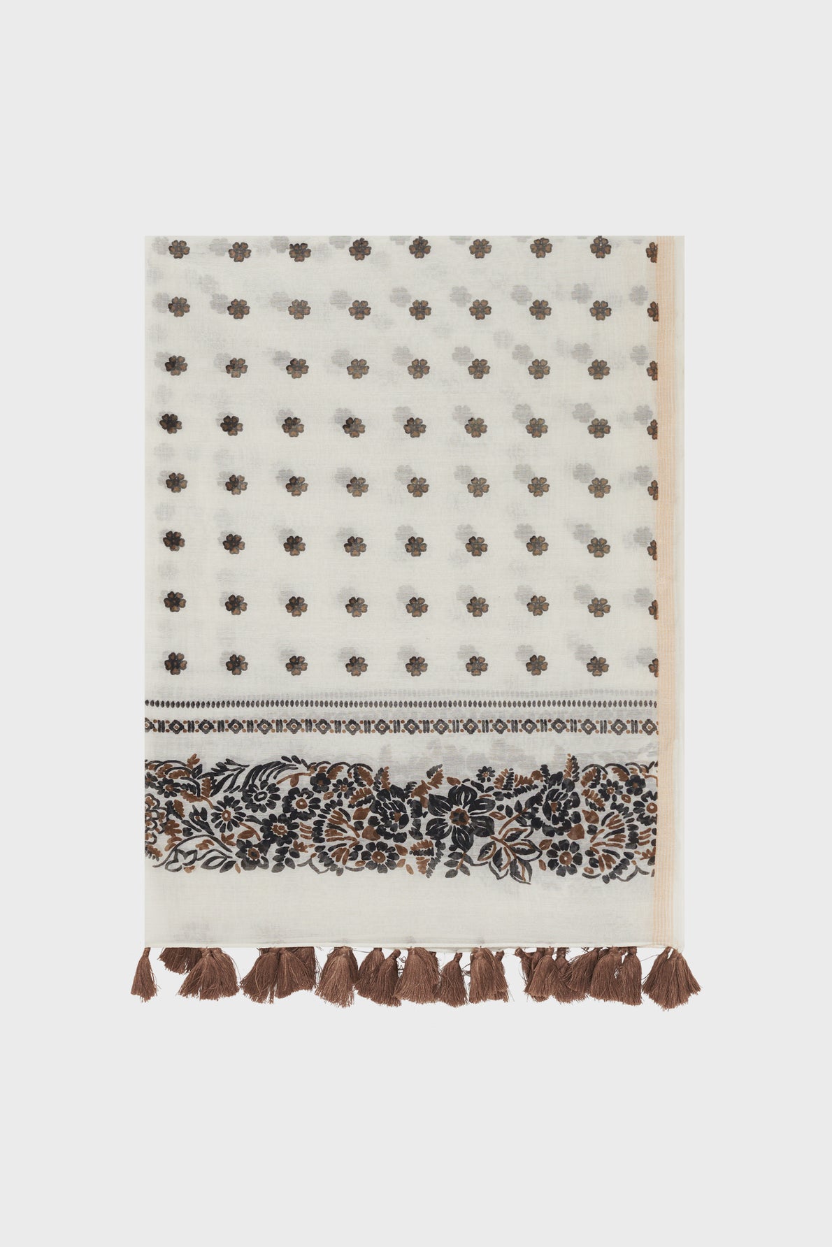 A cream-colored étole Daphné with a small brown floral pattern, a decorative border featuring intricate brown and black designs, and brown tassels along the edge. Crafted in a luxurious blend of coton et soie, this élégante étole florale adds effortless sophistication to any ensemble.
