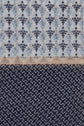 This fabric, reminiscent of a foulard Dalma, features two striking patterns: the top half displays blue floral motifs on a light background, while the bottom half is adorned with small white crescent shapes on a dark blue ground. Thin brown lines with subtle motifs géométriques elegantly separate the two sections.