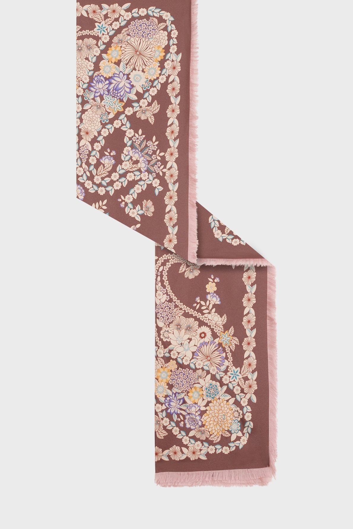 A long, rectangular scarf with fringed edges, featuring a motif floral in pastel colors on a muted mauve background.
