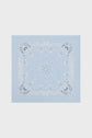 A light blue carré Dayana bandana featuring a classic white paisley pattern with floral and decorative elements, displayed flat against a plain, light background.