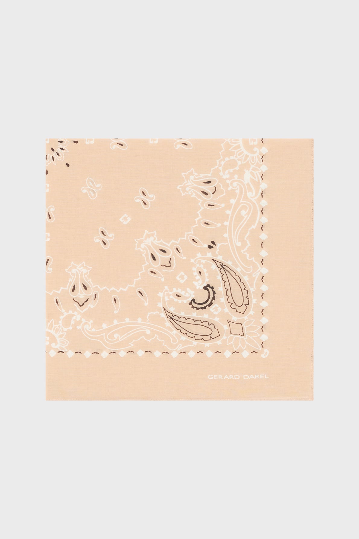 A folded beige foulard coton with a white and brown paisley pattern, featuring the text GERARD DAREL in white in the lower right corner, reminiscent of the élégant carré Dayana, displayed on a light gray background.