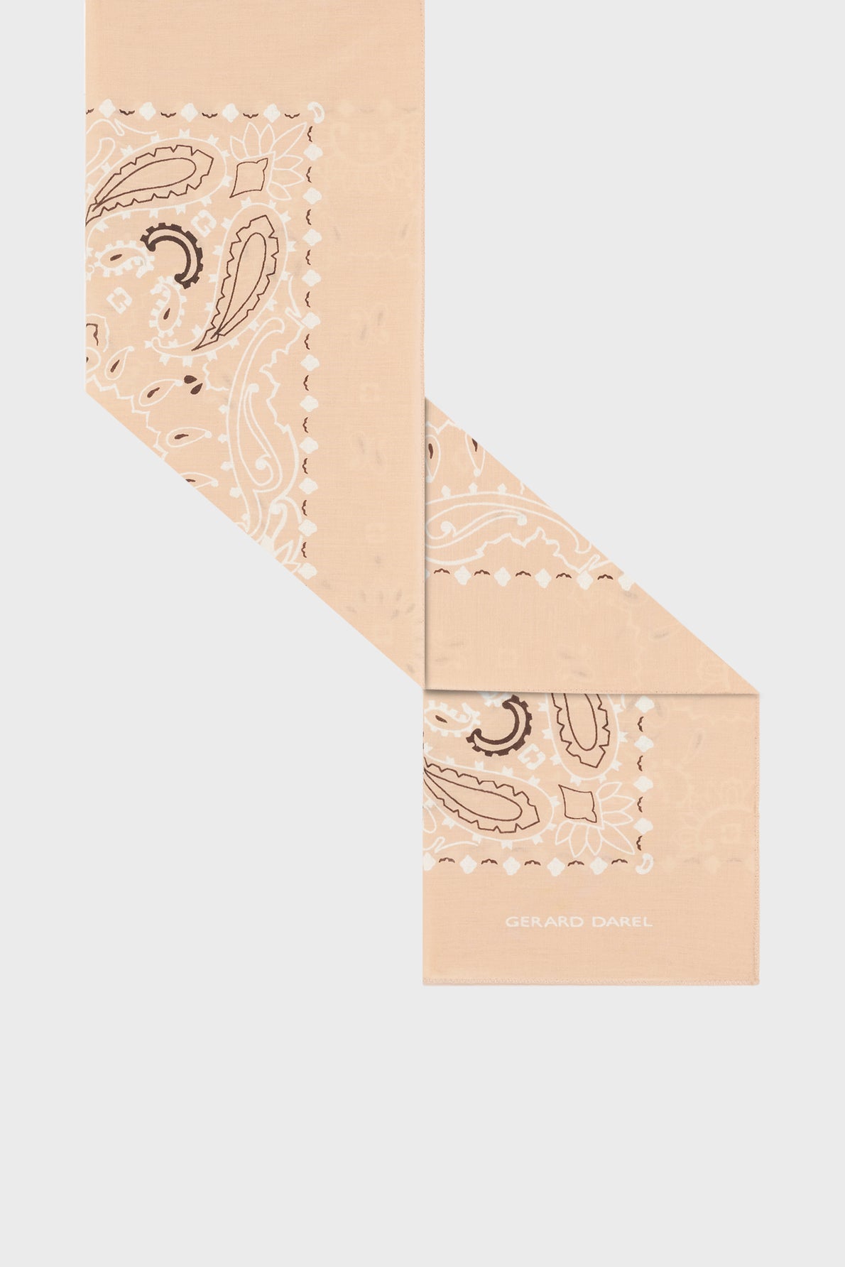 A beige bandana-style scarf with a paisley imprimé bandana pattern, folded in a zigzag shape. The words GERARD DAREL are printed in white on one corner of this elegant foulard coton carré Dayana.