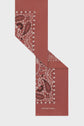 A rust-colored rectangular foulard coton scarf featuring a white and black paisley and floral motif along one edge, reminiscent of an imprimé bandana style, with the brand name GERARD DAREL printed in white at one end.
