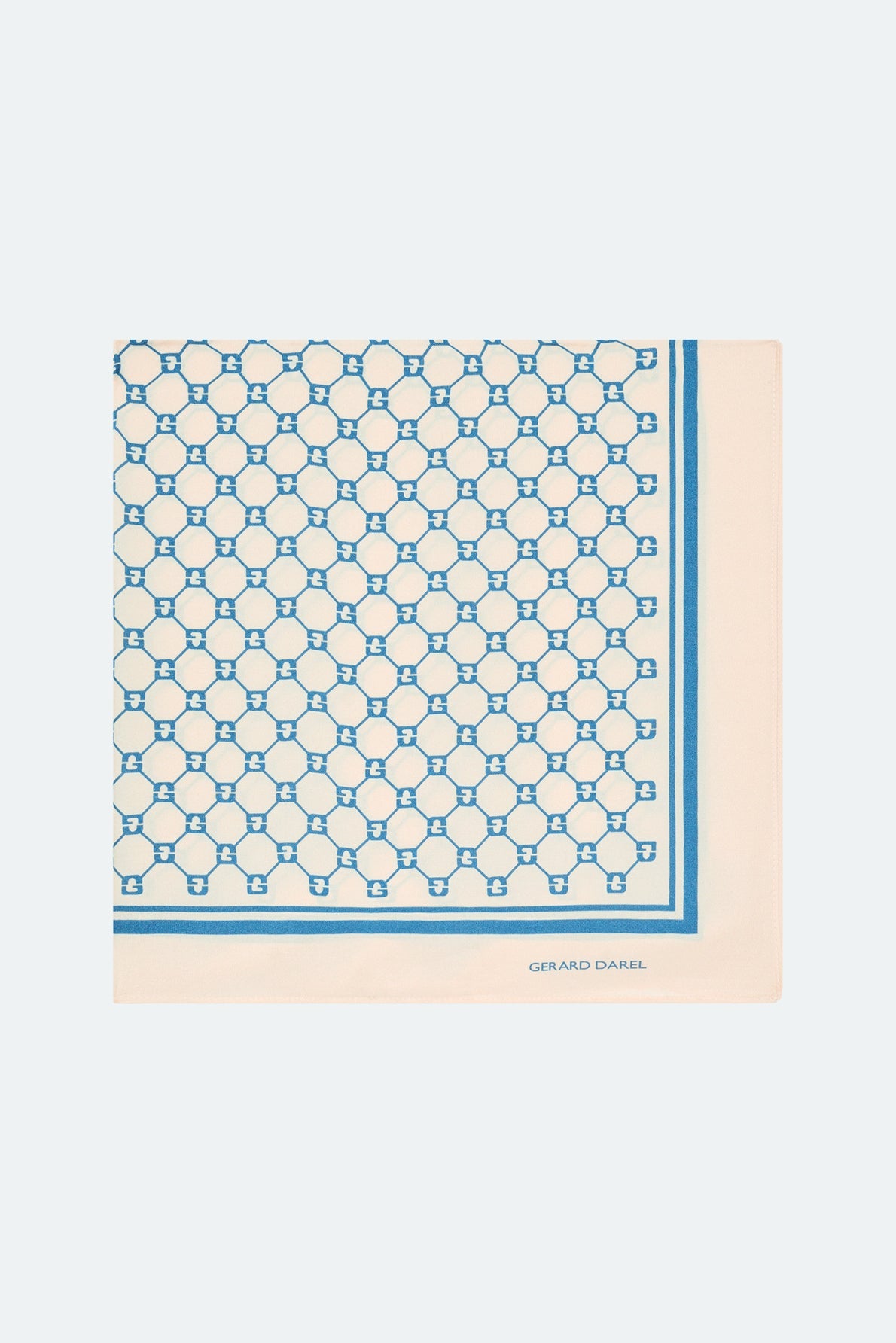 A square silk scarf, or carré soie, with a white background and blue geometric pattern, bordered by a striking blue stripe. The brand name GERARD DAREL and the distinctive monogramme GD are printed in blue in one corner, making this piece a refined accessoire cheveux or the perfect addition to your ensemble.