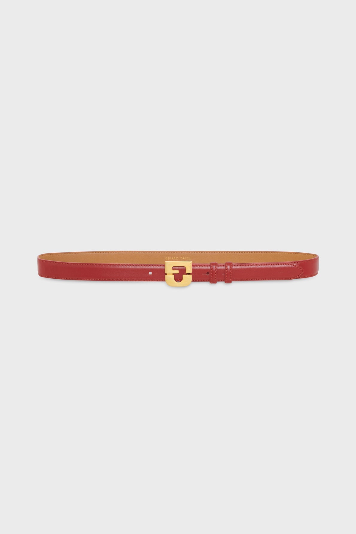 A slim red ceinture en cuir with a gold rectangular buckle, displayed on a plain white background, perfect for adding a touch of elegance to any look.