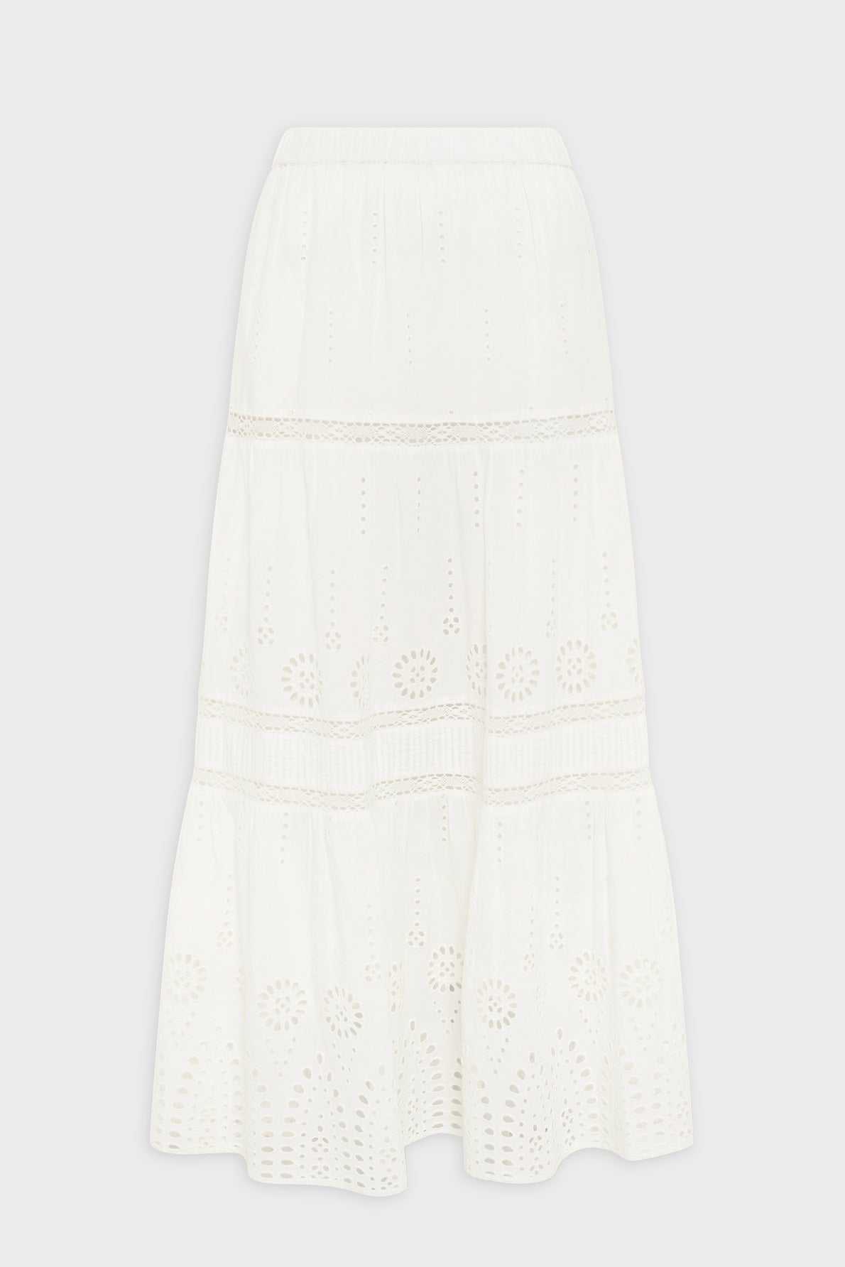 White, midi-length skirt with an elastic waistband, featuring eyelet embroidery in floral and circular patterns and tiered sections with lace trim. Skirt is displayed against a plain white background.