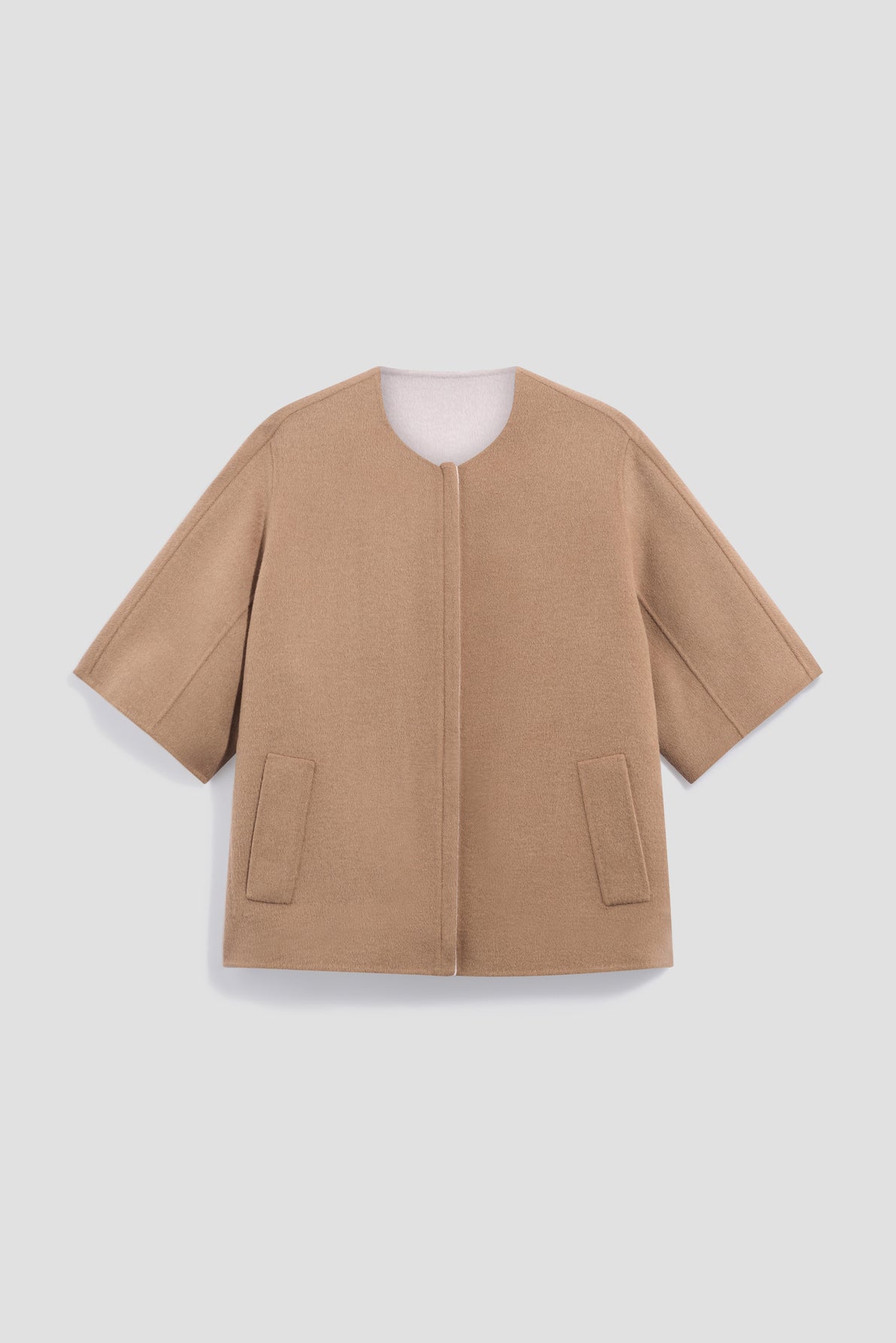 Camel-colored, short-sleeve, collarless manteau court crafted from luxurious laine double face, featuring front patch pockets, a straight hem, and a minimalist open-front design, displayed on a plain light background.