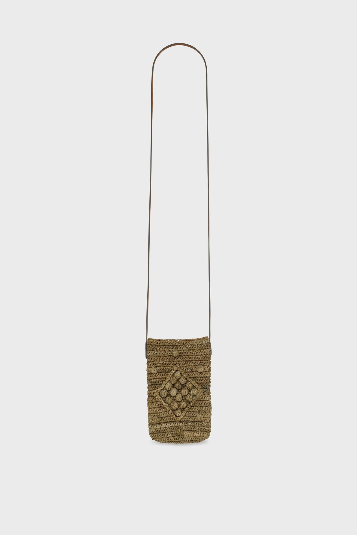 A small woven straw crossbody bag with a long thin brown strap and a decorative diamond motif crocheté pattern on the front, set against a plain white background—an accessoire tendance perfect for carrying your essentials in style.