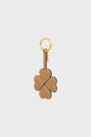 Tan leather porte-clé trèfle shaped like a four-leaf clover, with each leaf formed by a heart. This elegant porte-clé cuir is attached to a gold keyring and clasp, set against a plain light background.