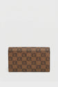 A brown portefeuille Gerard Darel featuring a repeating geometric pattern in dark brown tones on une toile enduite monogrammée, displayed upright against a plain white background, makes for an accessoire élégant.