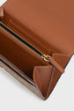 Open brown leather portefeuille Gerard Darel with gold zipper, showing several compartments and card slots. This accessoire élégant is photographed from above against a light background.