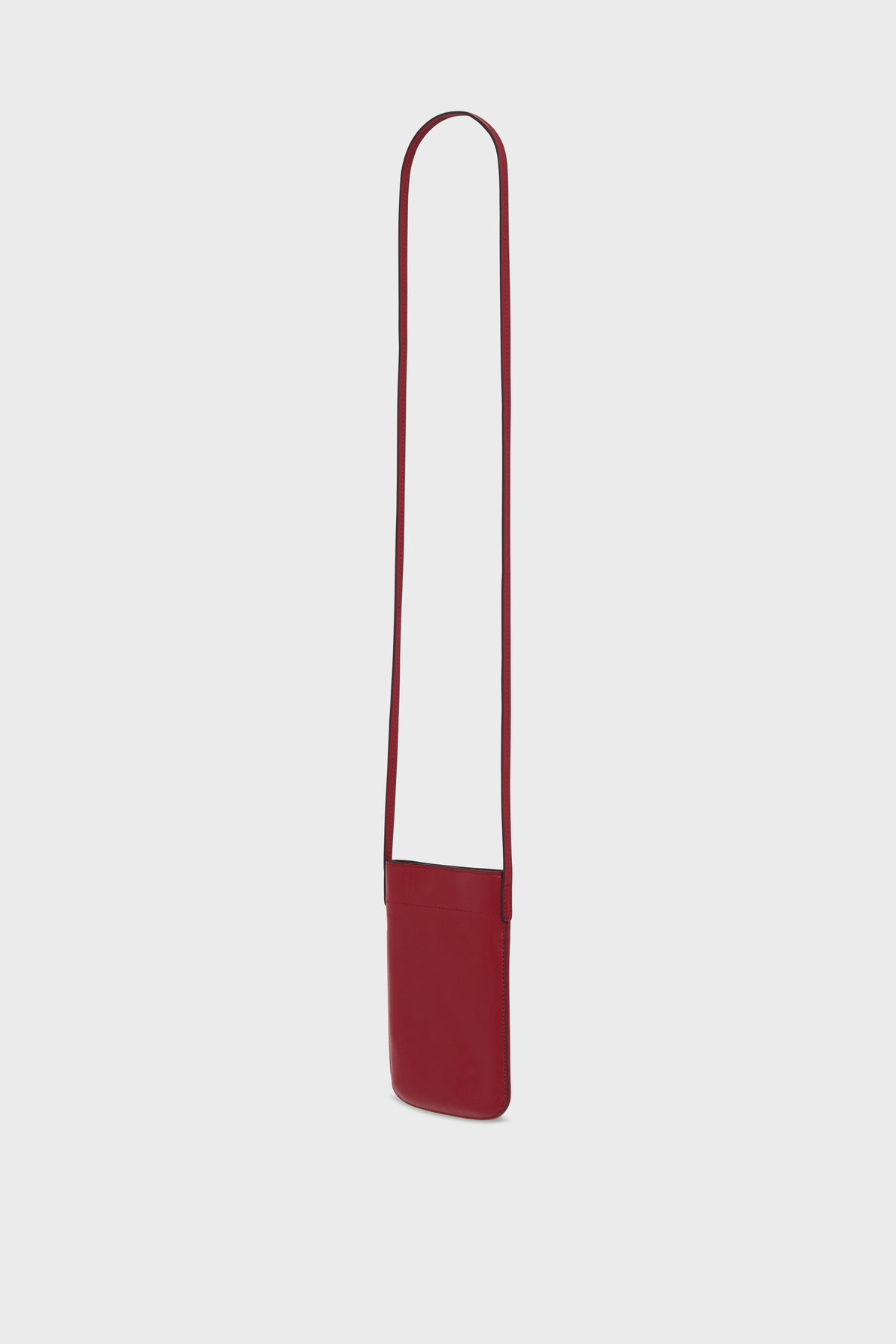 A small, rectangular red sac bandoulière crafted from cuir de vachette, featuring a long, thin strap and designed as a chic porte téléphone, displayed upright against a plain light gray background.