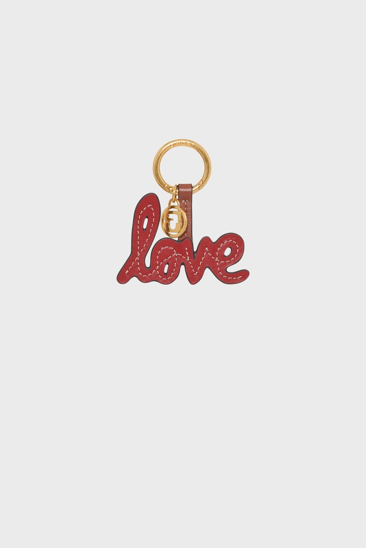 A gold keyring with a red leather charm spelling the word love in cursive letters, crafted from supple cuir de vachette and attached by a small strap, making this porte-clé LOVE both elegant and unique.