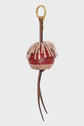 Round, red and pink woven porte-clé pompon with layered leather fringe on top, two long brown leather strips hanging below, and a gold keyring attached to a brown leather loop—an eye-catching porte-clé en cuir that makes the perfect accessoire sac.