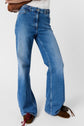 Person wearing high-waisted, blue wide-leg jeans and brown shoes with red and black laces, standing against a plain white background.