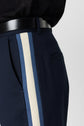 Person wearing a pantalon coton bleu marine with a light blue and white side stripe, a black belt, and a black shirt. Only the waist and upper thigh area are visible.
