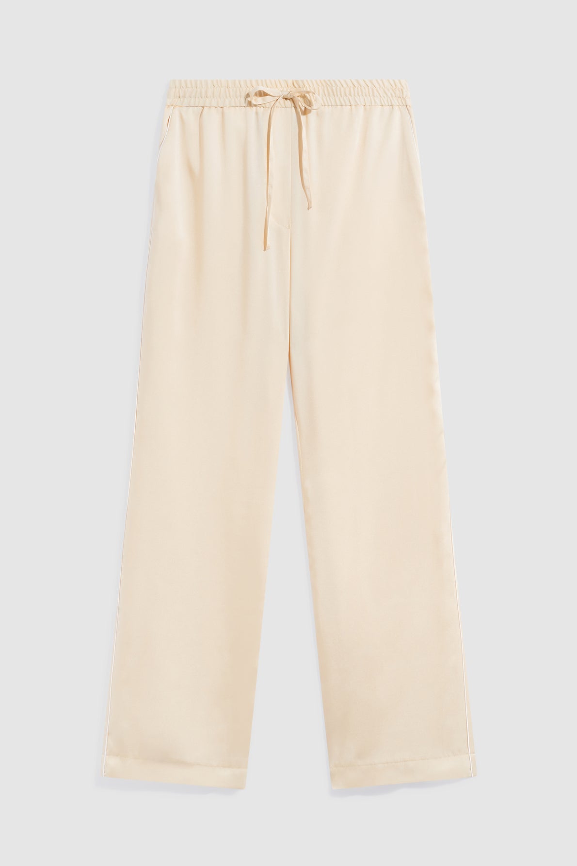 Beige satin pajama pants (pantalon satiné) with an elastic waistband (taille élastiquée) and drawstring, laid flat on a light gray background. The pants have straight legs and a relaxed fit.