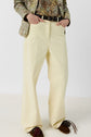 A person wearing high-waisted, wide-leg cream pants reminiscent of a pantalon femme, a floral printed jacket, a black belt, and brown shoes with decorative details. Their hands are in their pockets and their face is not visible.
