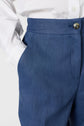 A person wearing a white shirt and blue trousers stands with one hand in their pocket. The image is cropped to show only the torso and upper legs.