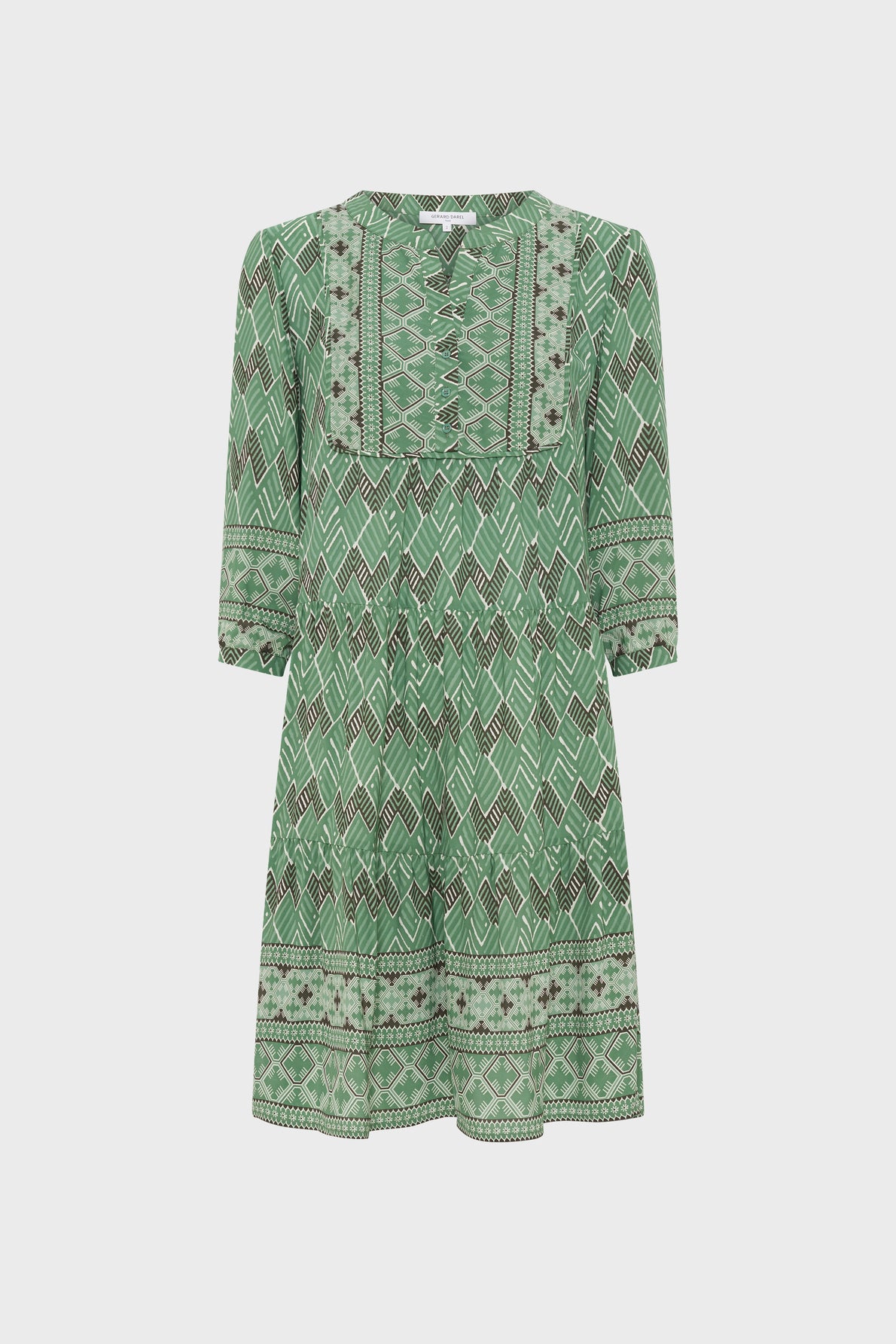 Green dress with a motif géométrique, three-quarter sleeves, and a loose, knee-length fit. This robe courte femme features intricate designs around the neckline, hem, and sleeve cuffs, creating a subtle style bohème perfect for any occasion.