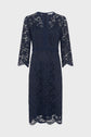 Navy blue knee-length lace dress with three-quarter sleeves, scalloped edges, and a fitted waist. This robe élégante features a floral lace overlay and a subtle V-shaped neckline with a small back zipper.