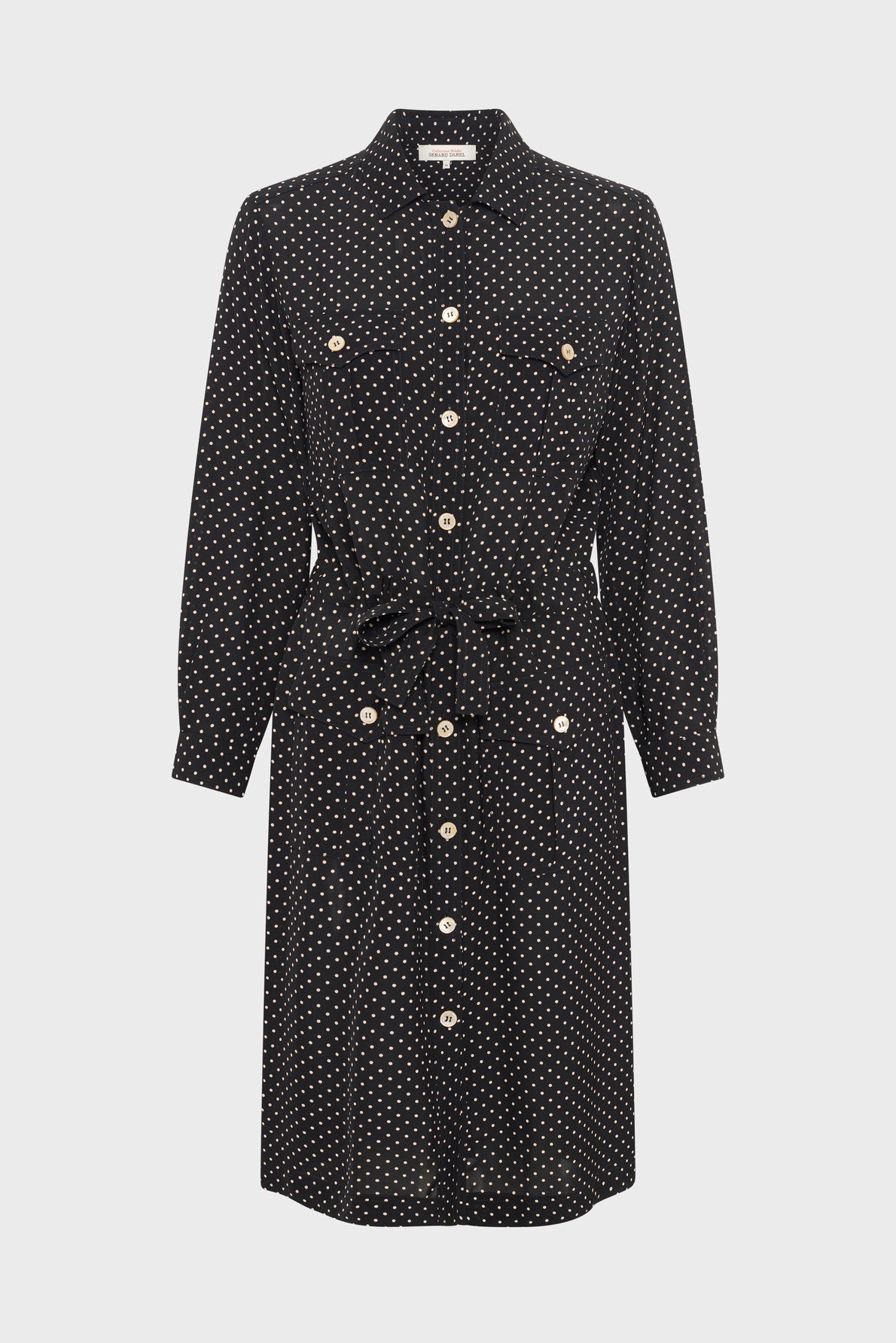 A knee-length, long-sleeve black robe chemise à pois crafted from soft viscose haboutaï, featuring white polka dots, a button-down front, two chest pockets, a collar, and a waist tie.