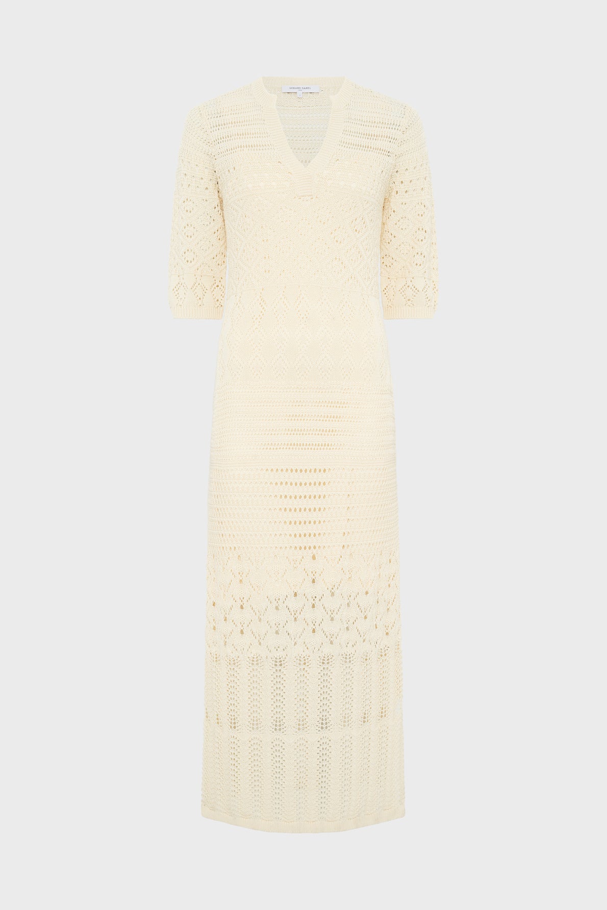 Cream-colored, knee-length crochet dress with short sleeves and a V-neckline, displayed on a plain light background. The dress features intricate, semi-sheer knit patterns throughout.