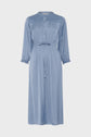 Light blue, long-sleeve midi dress with a button-up front, cinched waist with tie belt, pleated detailing on the chest, and ruffled cuffs. The dress has a soft, flowy fabric and a modest collar.
