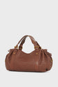 A brown sac à main crafted from cuir d’agneau tressé with double handles, gold hardware, and side drawstring details, beautifully showcasing the savoir-faire de la Maison, displayed on a light background.