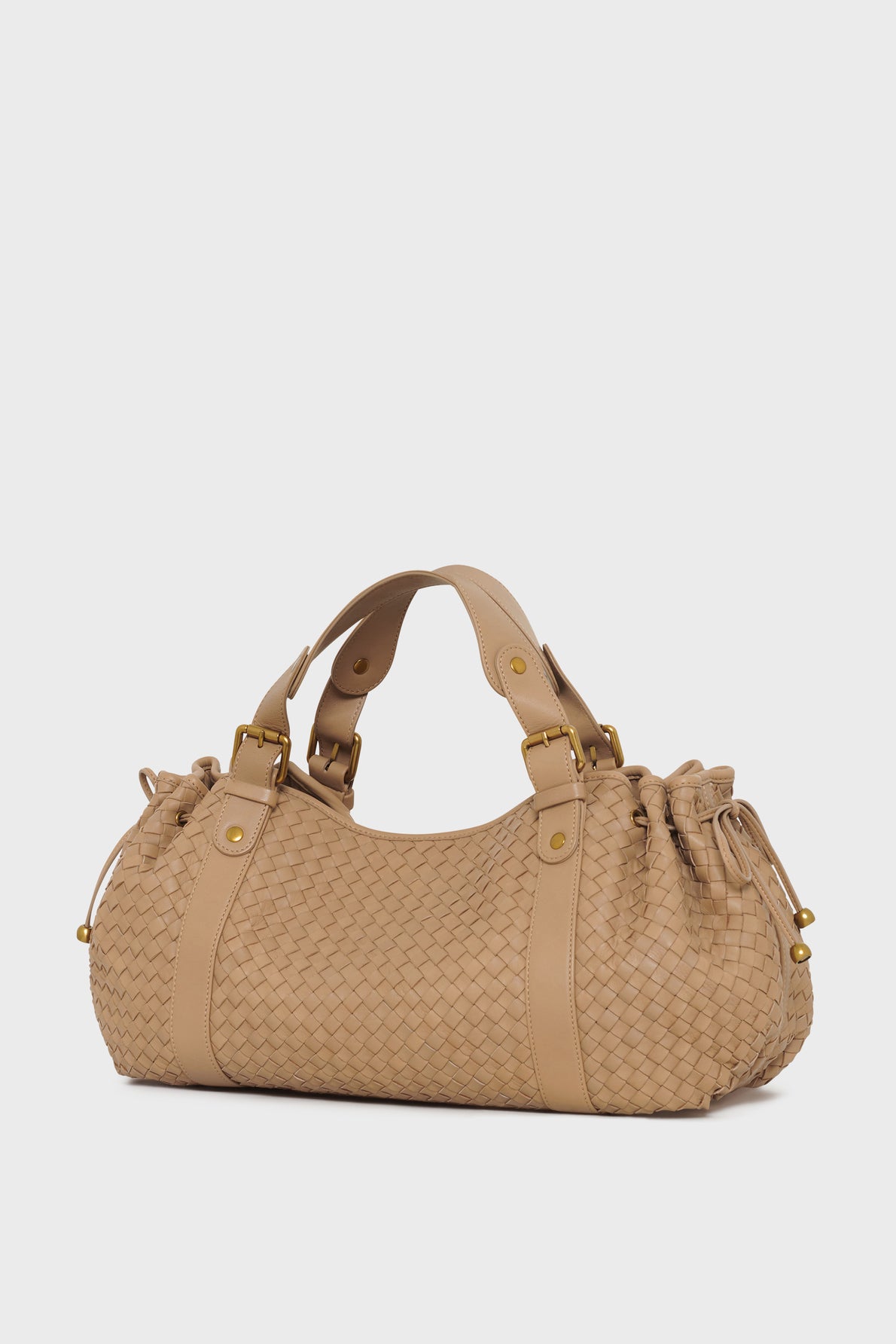 Beige sac à main tressé en cuir d’agneau avec double poignées, finitions dorées, et détails à cordons de serrage sur les deux côtés, présenté sur un fond blanc épuré. Idéal pour accompagner vos essentiels 24H.