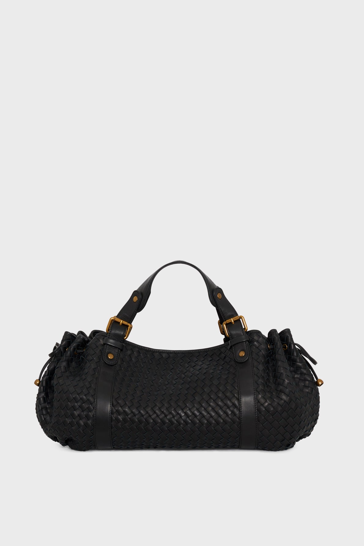 A black sac à main tressé in woven cuir d’agneau with gold hardware, two top handles, and ruched sides, set against a plain light gray background—a testament to savoir-faire artisanal.