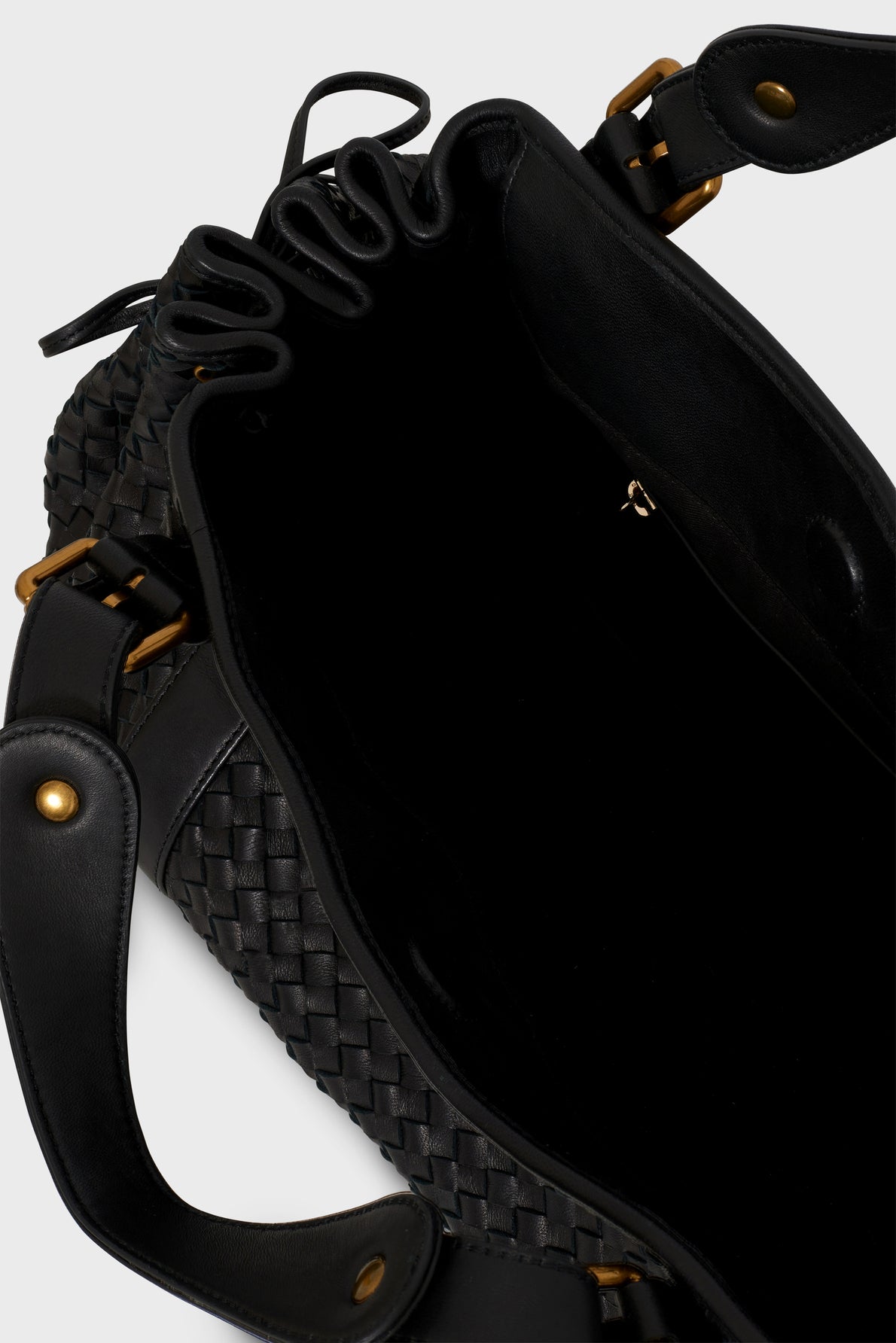 An open black sac à main tressé in woven cuir d’agneau with gold hardware and a black interior, showcasing the spacious inside and the exquisite savoir-faire artisanal visible in the basket-weave design on the exterior.