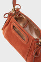 A rust-colored sac à main in élégant cuir velours with a cut-out handle, side drawstrings, and a metallic gold interior lining, shown from an angled top view.