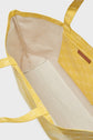 Open yellow cabas en toile tote bag with a beige fabric interior and an inner yellow pocket featuring a geometric pattern. The sac Le LOLITA has two handles and a visible brown logo tag on the pocket.