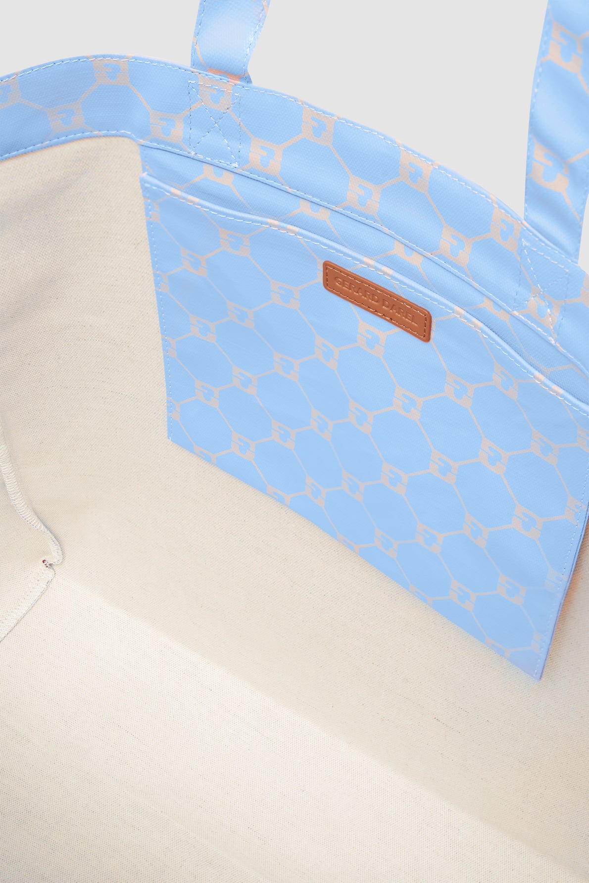 Open cabas en toile tote bag with a cream fabric interior and a blue patterned pocket attached inside, featuring tan logo accents and brand label.