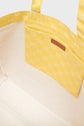 Interior of a beige sac été tote bag with a yellow patterned pocket and yellow handle. The pocket features a small brown leather label, adding a touch of elegance to this cabas en toile.