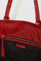 Close-up of a handbag with red leather trim, gold zipper, black fabric body, and a red leather label that reads GERARD DAREL. The image focuses on the upper part of the bag and its handle attachments.