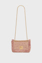 Pink tweed sac bandoulière with fringe edges, gold-tone chain strap, and a gold-tone clasp on the front. Showcasing exquisite savoir-faire artisanal craftsmanship, the bag is displayed against a plain white background.
