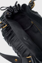 Open black cuir de vachette noir handbag with fringe detail, gold hardware, visible zipper pocket inside, and fabric lining. This sac à main frangé features a magnetic snap closure and an adjustable shoulder strap.