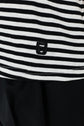 A close-up of a tee-shirt Mayane featuring rayures noires et blanches and a small embroidered black letter G near the hem, paired with solid black pants. The manches courtes papillon add a subtle feminine touch to the classic striped design.