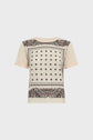 A short-sleeve beige t-shirt femme with a square decorative pattern on the front, featuring small motif floral and intricate bordered designs in black and red for an elegant t-shirt effet foulard look.