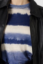 A person wearing a black leather jacket over a blue and white horizontally striped shirt with a tie-dye pattern.